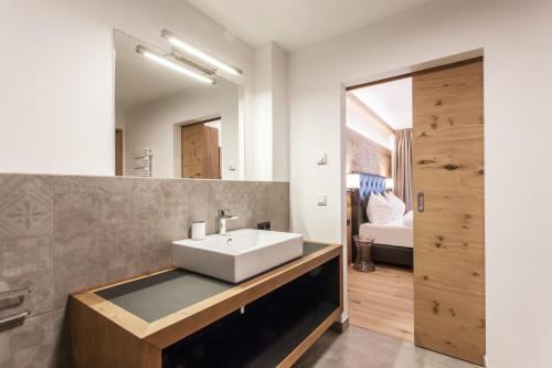ein Bad mit einem Waschbecken und einem Spiegel in der Unterkunft Hubertus Logis Apartments in Brixen im Thale