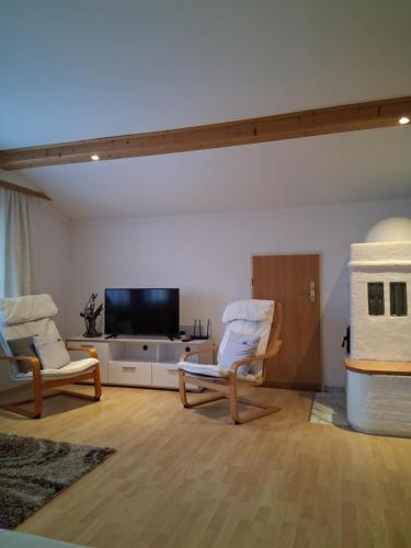 Una sala de estar con dos sillas y un televisor de pantalla plana. en Mani‘s Appartements, en Radstadt
