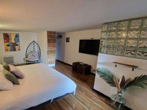 Un dormitorio con una gran cama blanca y un televisor de pantalla plana. en Chambre Deborah indépendante, en Le Pradet