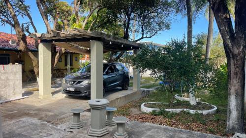 un coche aparcado bajo un pabellón en una entrada en El Gringo Banheiro Compartilhado, en Cabo de Santo Agostinho