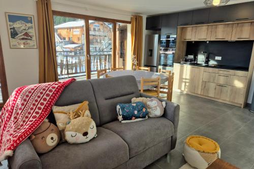 ein Wohnzimmer mit einer Couch mit Kissen darauf in der Unterkunft Spacieux appartement au pied des pistes in La Feclaz
