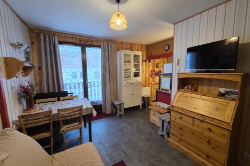 ein Wohnzimmer mit einem Esstisch und einem TV in der Unterkunft Appartement idéal famille - pied des pistes in Les Déserts