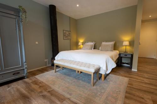 a bedroom with a large bed and a bench at Herberg De Fazant in Oudemolen