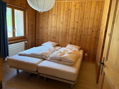 Bett in einem Zimmer mit Holzwänden und einem Fenster in der Unterkunft Cozy Alpine Apartment Davos Wiesen in Davos