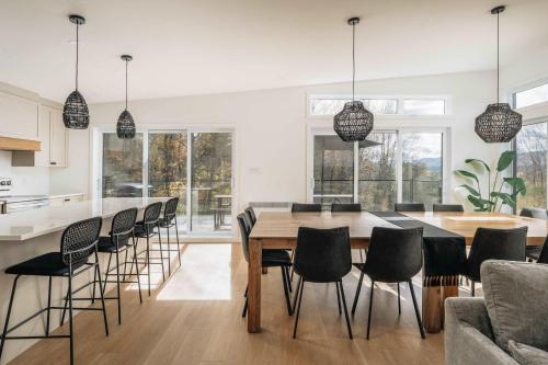 a kitchen and dining room with a wooden table and chairs at Chalet a Samia - Spa, luxury, Jay Peak view in Mansonville