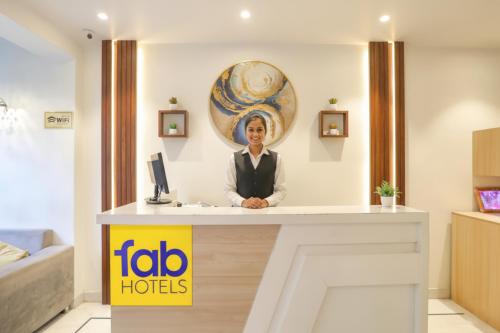 a woman standing at a reception desk in a hotel room at FabHotel JHS Studio in Gurgaon
