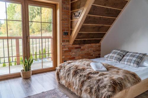 un lit dans une pièce avec un mur de briques et des fenêtres dans l'établissement Babcia Góralka house, à Bukowina Tatrzańska