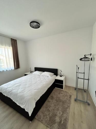 ein Schlafzimmer mit einem großen Bett mit weißer Bettwäsche und einem Teppich in der Unterkunft Noir Suite in Şelimbăr