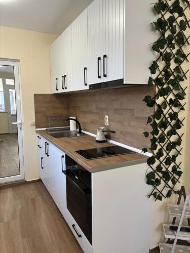 a kitchen with white cabinets and a black stove top oven at Уют in Sandanski