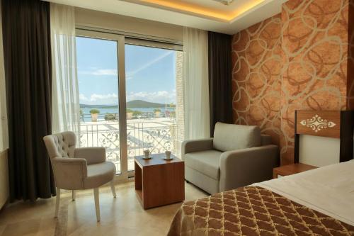 a hotel room with a bed and a chair and a window at Cunda Kivrak Hotel in Ayvalık