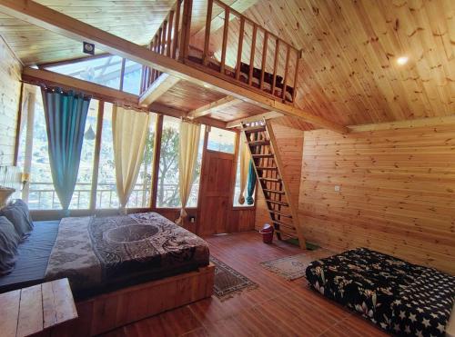 a bedroom with a bed and a staircase in a cabin at The Cedar Nook Tree House in Jibhi