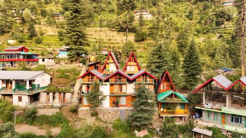 a group of houses on a hill with trees at The Cedar Nook Tree House in Jibhi