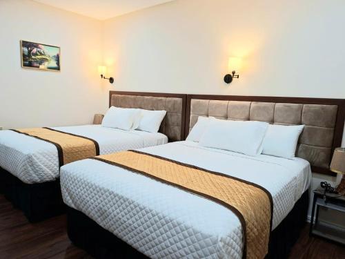 ein Hotelzimmer mit zwei Betten mit weißen Laken in der Unterkunft Rey'z Hotel and Suites in Vreed en Hoop