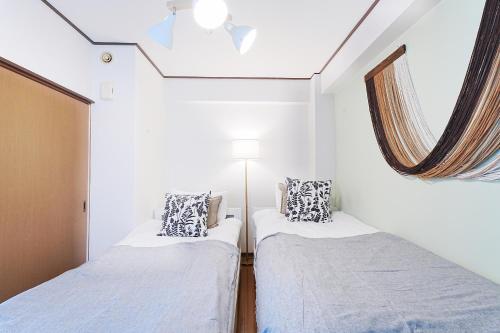 two beds in a small room with a window at Tomo House Yoyogi 301 - from 4 minutes station 代々木 301 駅から徒歩4分 in Tokyo