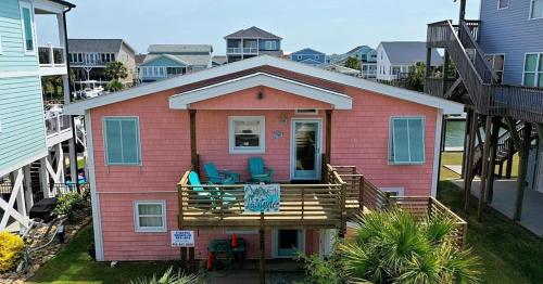 a pink house with two chairs on a deck at Changes In Latitude home in Holden Beach