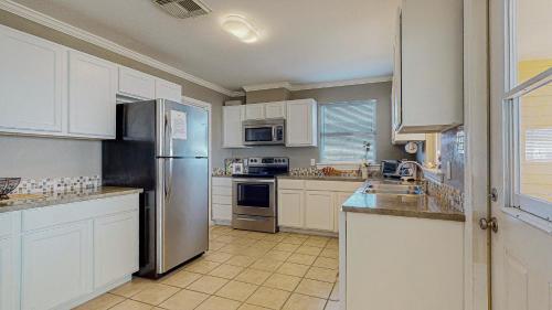 a kitchen with white cabinets and a stainless steel refrigerator at Sun and Moon in Port Bolivar