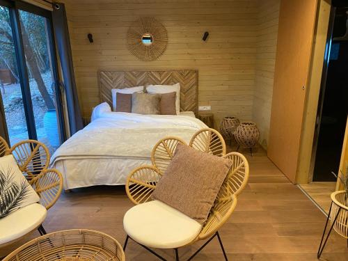 a bedroom with a bed with chairs and tables at Lodge Slow Life - Mas de Rey in Arpaillargues-et-Aureillac