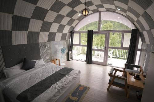 Un dormitorio con una cama y una ventana grande en The Lush Pods, en Jāmb