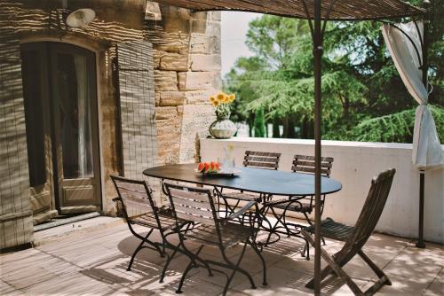 een tafel en stoelen op een patio met een parasol bij Van Gogh - Mas De Rey in Arpaillargues-et-Aureillac