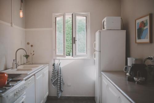 een keuken met een witte koelkast en een raam bij Rodin - Mas De Rey in Arpaillargues-et-Aureillac