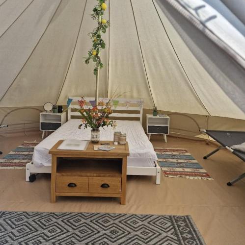 a tent with a bed and a table with flowers at I do glamping penhallow campsite Ltd in Truro