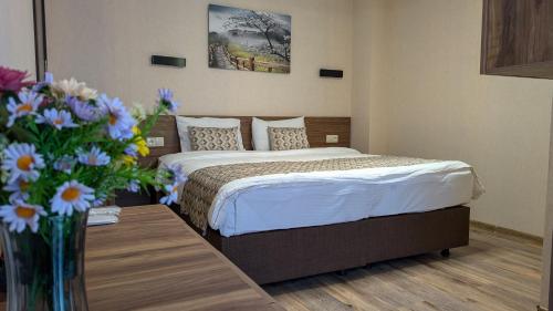ein Hotelzimmer mit einem Bett und einer Vase mit Blumen in der Unterkunft Krystal Resort Apartment A108 in Bakuriani