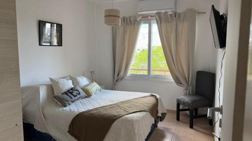 a bedroom with a bed with a window and a chair at Departamento Boulevares in Concepción del Uruguay