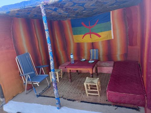 une tente avec un lit, une table et des chaises dans l'établissement Travel Oasis Merzouga Camp, à Merzouga
