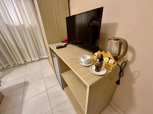 ein Schreibtisch mit einem Fernseher und einer Tasse Kaffee darauf in der Unterkunft pumaa pyramids giza INN in Kairo