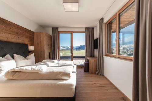 a bedroom with two beds and a large window at Hubertus Logis Apartments in Brixen im Thale