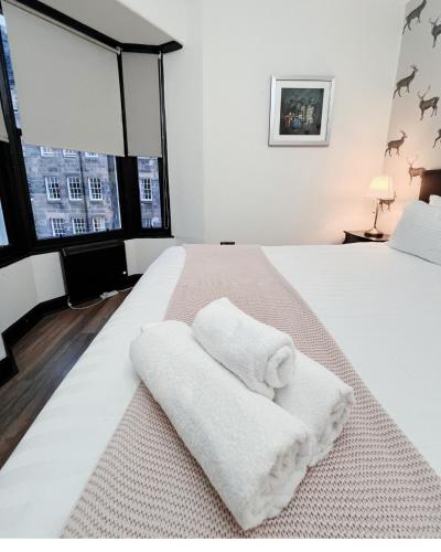 - une chambre blanche avec 2 serviettes sur un lit dans l'établissement Leith Apartment, à Édimbourg