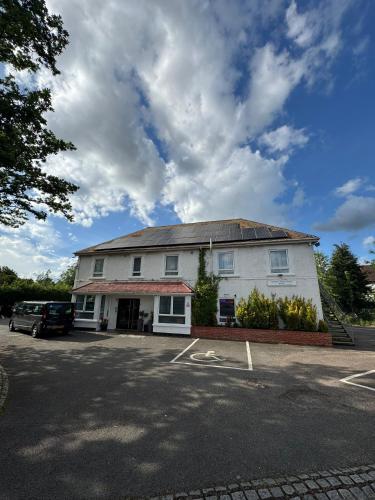 a white building with a car parked in a parking lot at The Gatwick White House Hotel in Horley