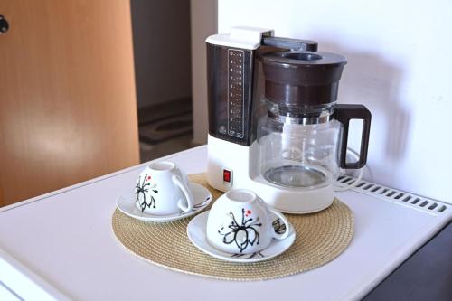 Una cafetera y dos tazas en un mostrador en Νηρηίδες so blue, en Arkitsa