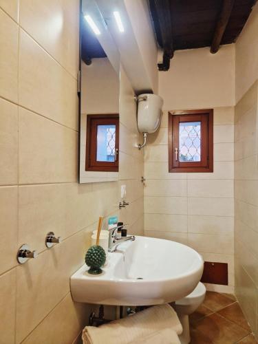 a bathroom with a white sink and two windows at La Magia del Borgo in Genzano di Roma
