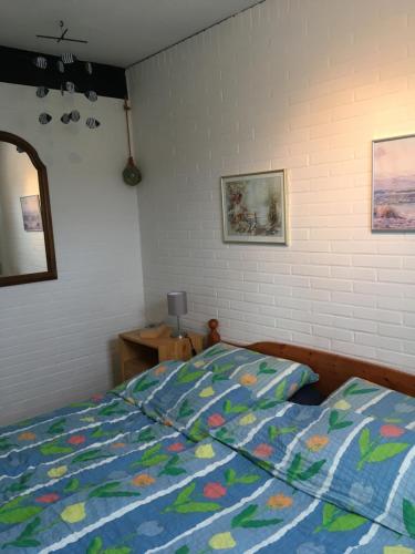 a bedroom with a bed with a comforter and a mirror at Friesenkoje Tossens in Butjadingen