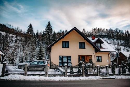 a house with a fence and a car in the snow at Kwatery prywatne u Danusi in Wierchomla Wielka