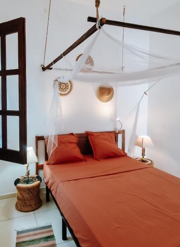 a bedroom with a bed with red sheets and a ceiling at Casa Cesaria Guest House in Sal Rei