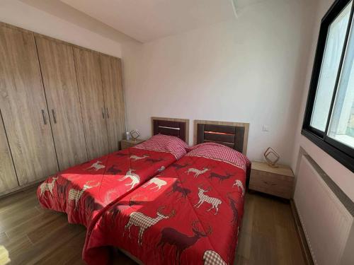 a bedroom with a bed with a red comforter at New Sweet Home Soukra in Sukrah