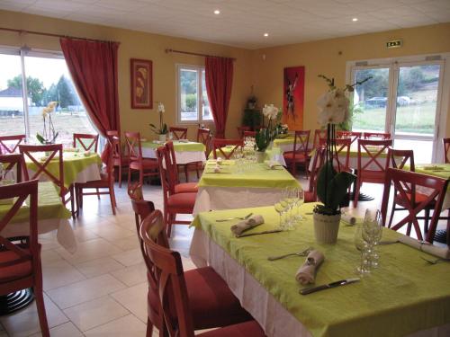 een restaurant met tafels en stoelen met groene tafelkleden bij Hôtel Le Colombier in Saint-Pantaléon-de-Larche