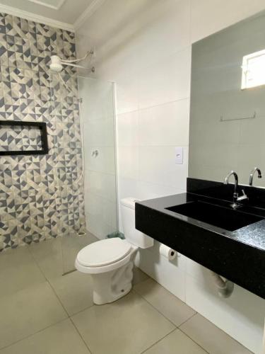 a white bathroom with a toilet and a sink at Parati - Hotel Pousada e Motel in Quatá