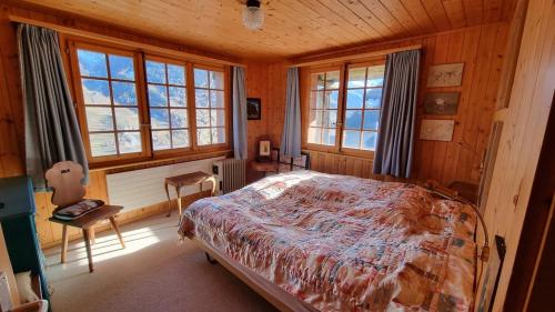 Un dormitorio con una cama en una habitación con ventanas. en Chalet le Moulin - calme, nature, cheminée, vue, en Liddes
