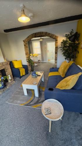 a living room with a blue couch and a table at Olivia's Cosy Cottage in Great Baddow