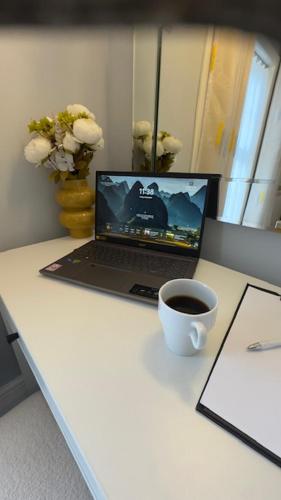 a laptop computer sitting on a desk with a cup of coffee at Olivia's Cosy Cottage in Great Baddow