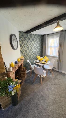 a dining room with a table and chairs and a clock at Olivia's Cosy Cottage in Great Baddow