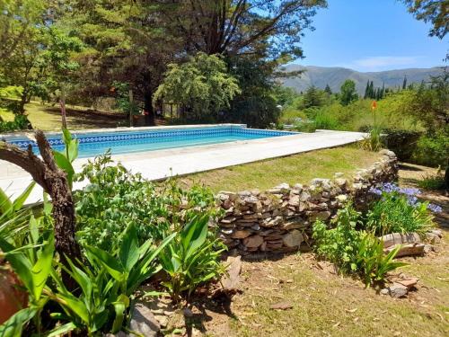 een zwembad in een tuin met een stenen muur bij Suspiro de Montaña in Casa Grande
