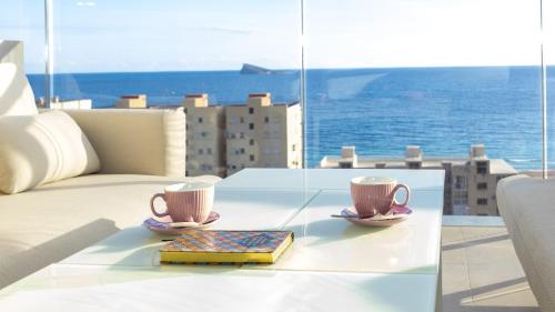 two coffee cups and a book on a table on a balcony at SUNSET SAILORS vibe apartment in Benidorm