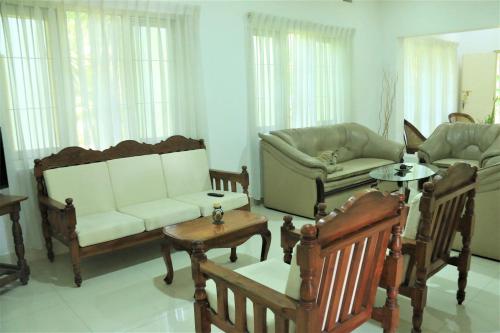 Una sala de estar con sofás y sillas y una mesa. en Villa Heritance, en Badulla