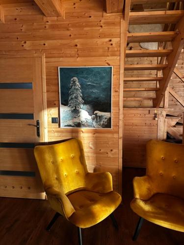 two yellow chairs in a room with a picture at Dom drewniany z sauną i jacuzzi w Szklarskiej Porębie in Szklarska Poręba