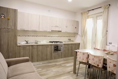 une cuisine avec des armoires blanches et une table avec des chaises dans l'établissement Villa Magiola Pompei, à Pompéi