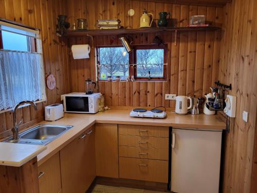 a kitchen with wooden walls and a counter with a sink at Vonarland hús með einu svefnherbergi in Stokkseyri